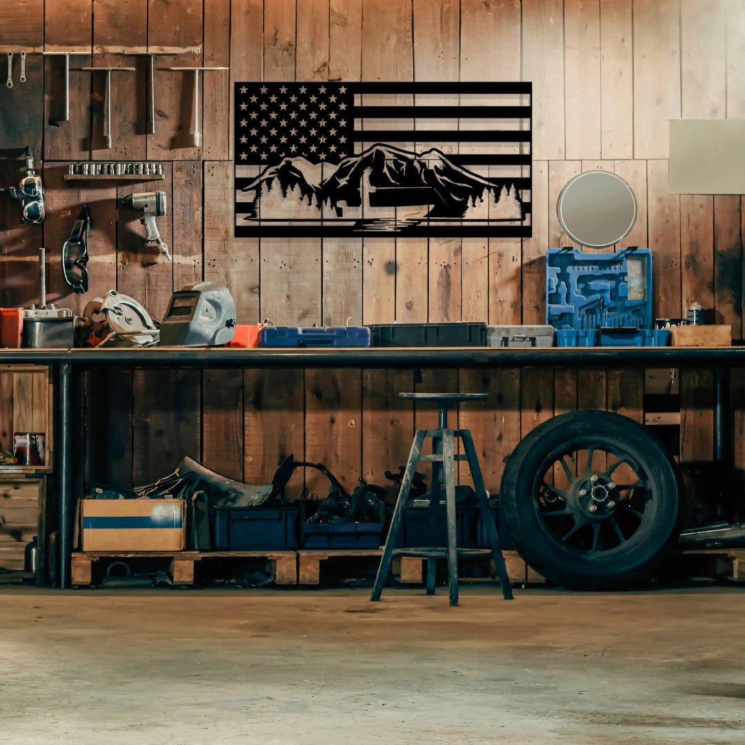 A rugged metal american flag wall panel with mountains and forest silhouettes decorates a rustic workshop wall, blending strength and nature in durable patriotic wall decor.