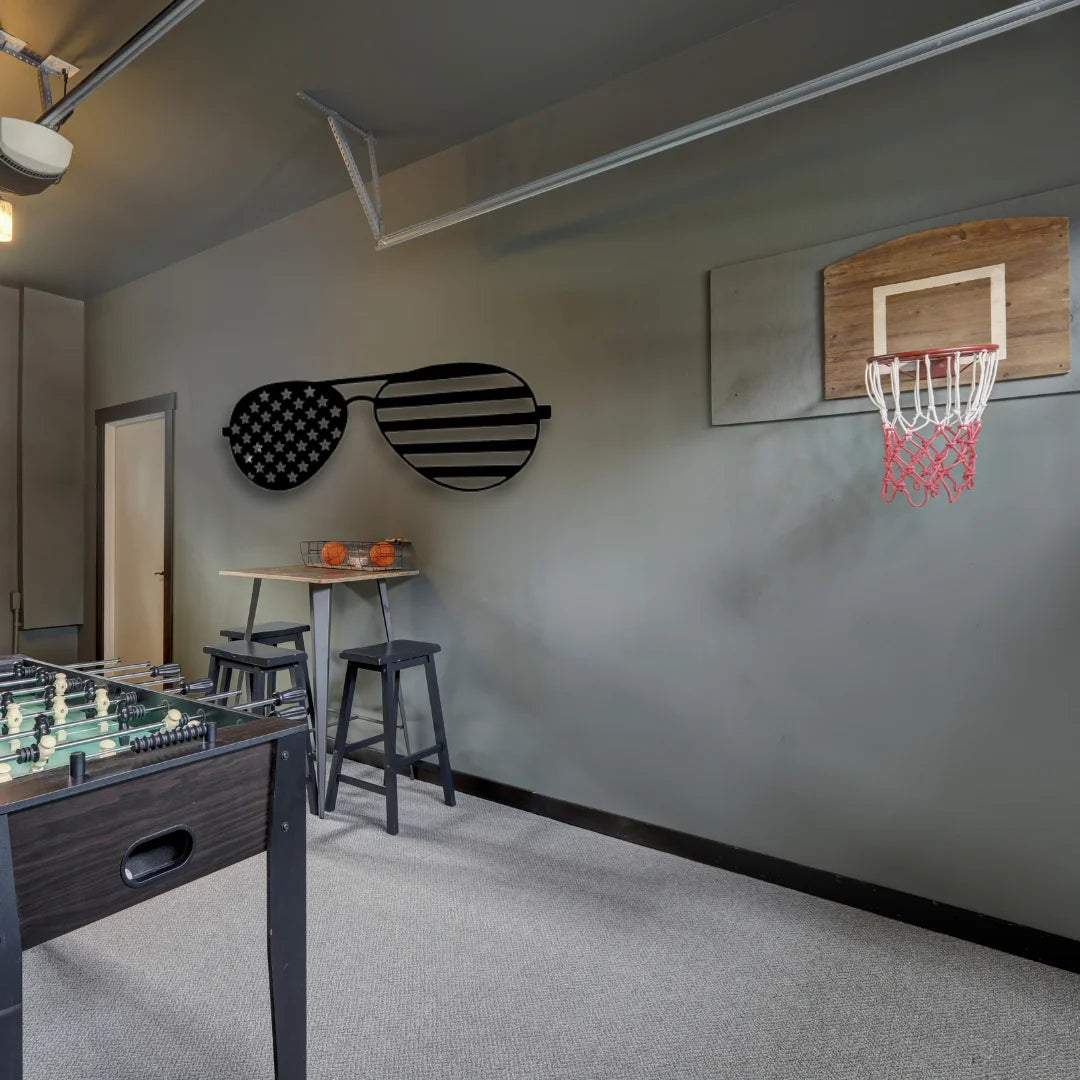 Oversized sunglasses with an American flag design in black metal add playful, patriotic energy to this modern game room wall.