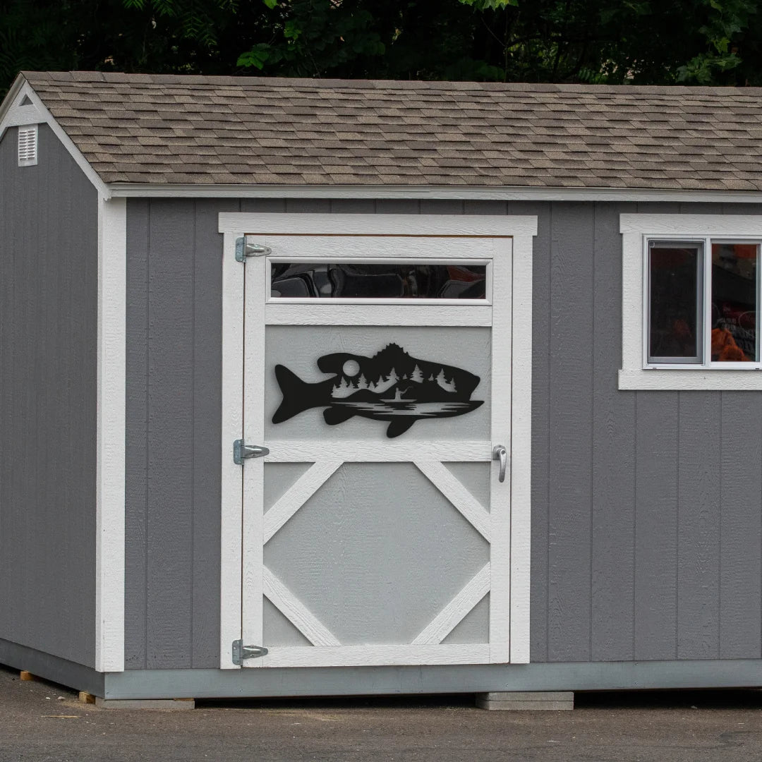 A bold black steel fish wall art decor shaped like a fish with trees and moonlight appears on a shed door, perfect for anglers or rustic backyard vibes.