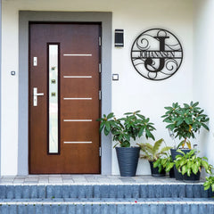 A stylish round metal initial signs plaque with swirling script and last name, adding a custom family touch to the front entrance wall.