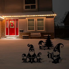 A charming winter lawn display with festive yard gnomes and Christmas props in black metal silhouette style adds whimsy to a snow-covered home exterior.