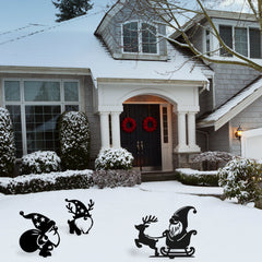 Three playful metal garden gnome decorations, including reindeer and sleigh designs, add holiday spirit to a snow-covered front lawn.