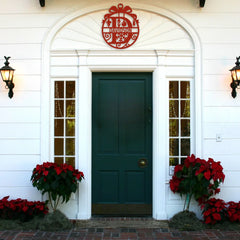 A festive red custom name monogram decorates the home’s entry arch, offering a personal touch to exterior holiday decor.