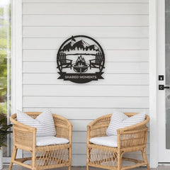 A round metal garden art piece featuring a firepit, two chairs, and mountains sets a cozy tone on a white porch, ideal for capturing meaningful memories.