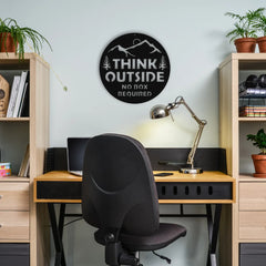 A round steel wall art with the quote “Think Outside – No Box Required” adds inspiration and edge to a modern workspace setup.