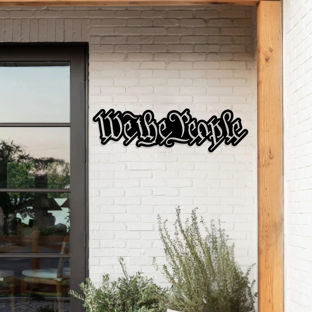 This bold-text custom metal signs outdoor piece stating “We the People” is mounted above a suburban garage, ideal for showcasing values with metal wall hanging decor.