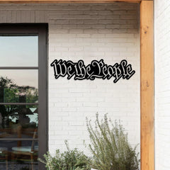 This bold-text custom metal signs outdoor piece stating “We the People” is mounted above a suburban garage, ideal for showcasing values with metal wall hanging decor.