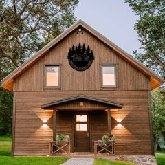 This welcome signs for lake house piece displays a cabin under pine trees and hangs proudly on a rustic cabin front, making it a favorite among cabin decorations collectors.