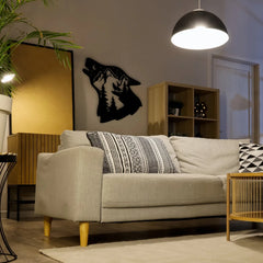 A howling wolf with mountain forest cutout in black metal creates a striking and moody accent on the living room wall, perfect for modern rustic decor.