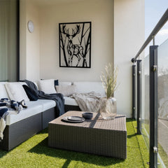 A tall metal wall hanging featuring a deer silhouette framed by trees adds a rustic charm to this cozy balcony nook.
