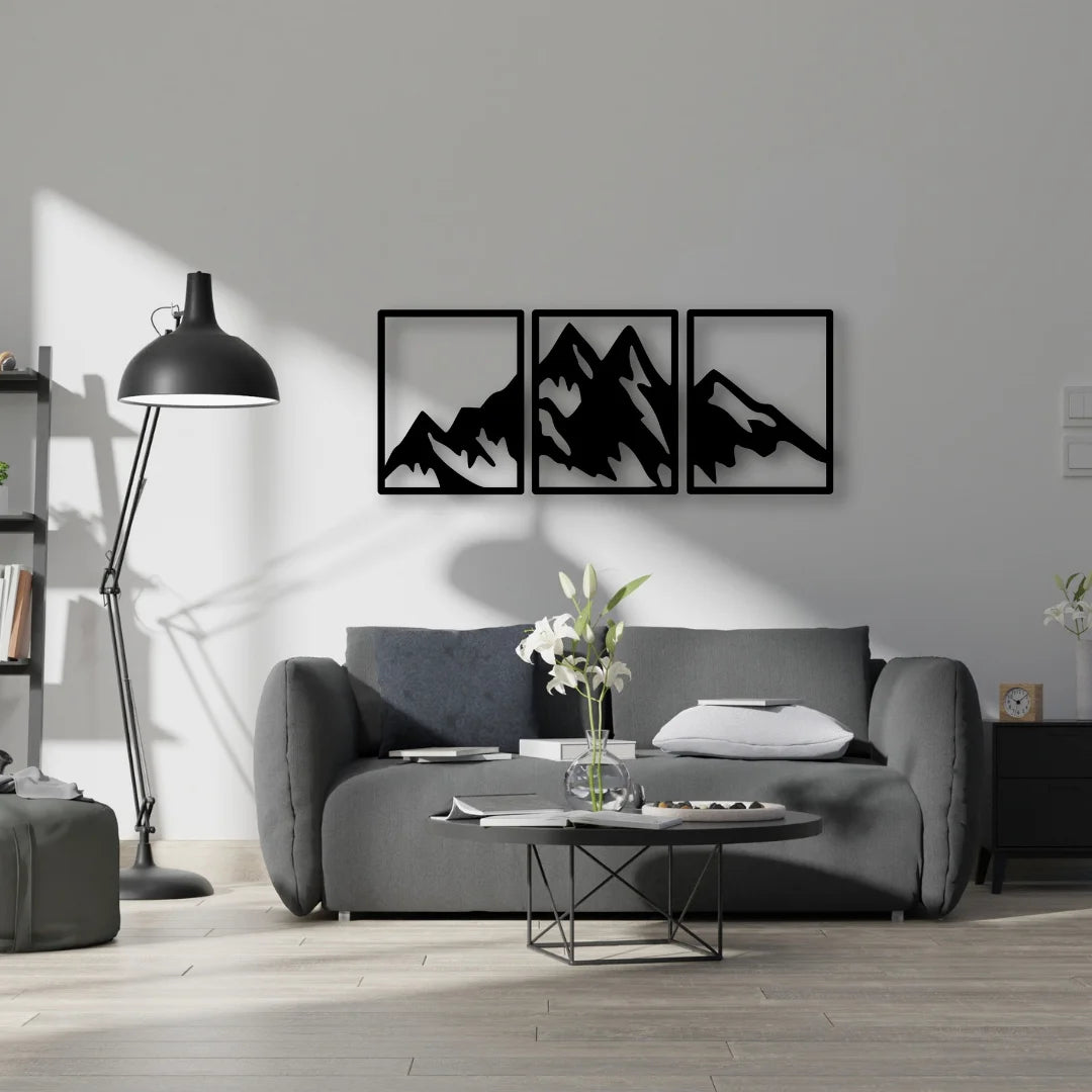 A bold black metal wall hanging triptych of mountain peaks brings symmetry and outdoor inspiration to a minimalist living space.
