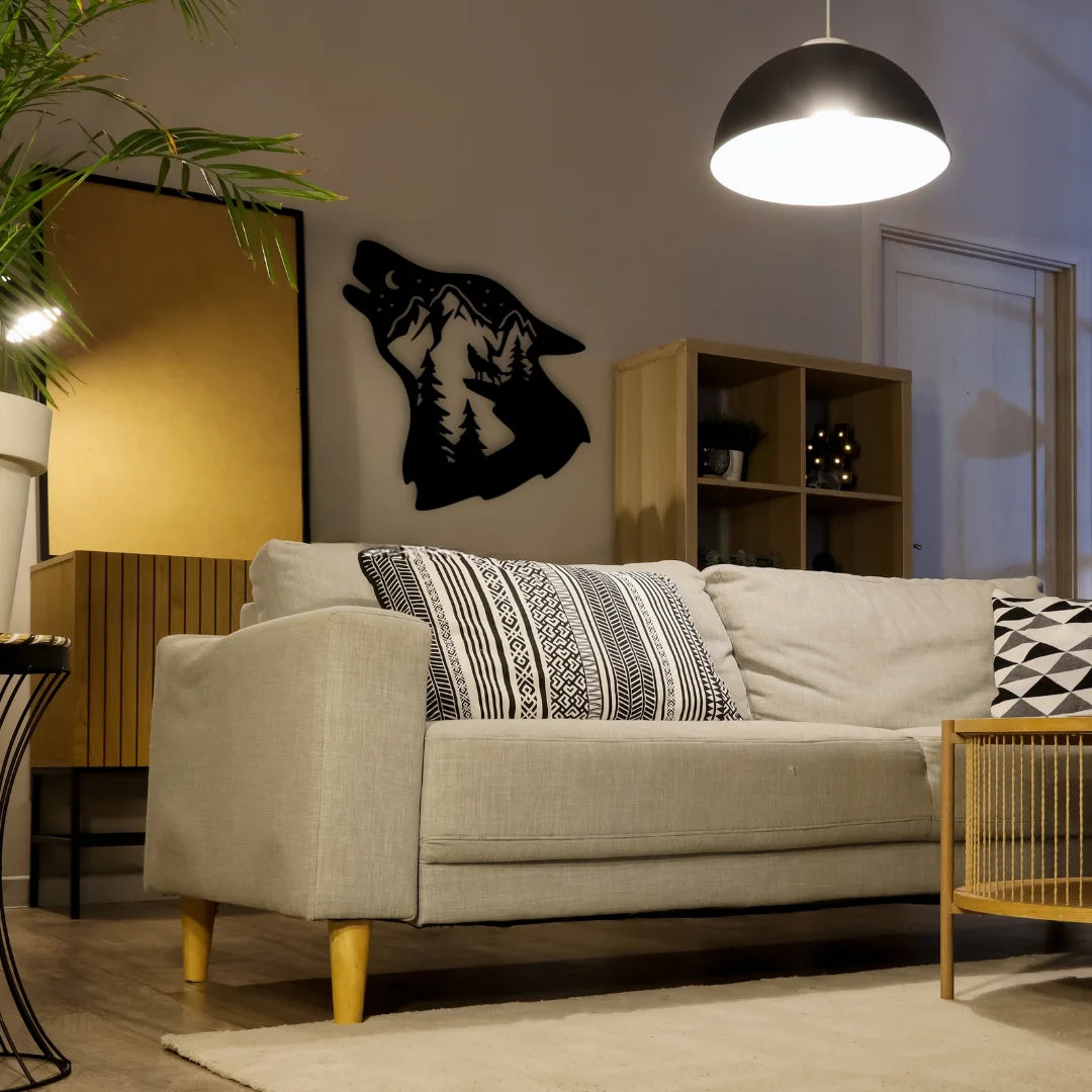 A howling wolf with mountain forest cutout in black metal creates a striking and moody accent on the living room wall, perfect for modern rustic decor.
