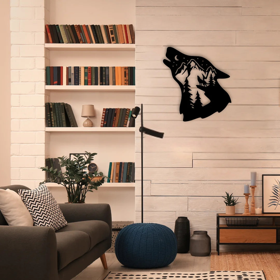 A cozy reading nook with a black metal wall ornament featuring a howling wolf and mountain scene, mounted on a pale wood wall above neutral rustic decor.
